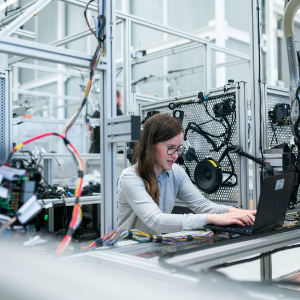 Women in technical field on a computer in an industrial space.